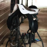 A black saddle on a saddle rack in storage.