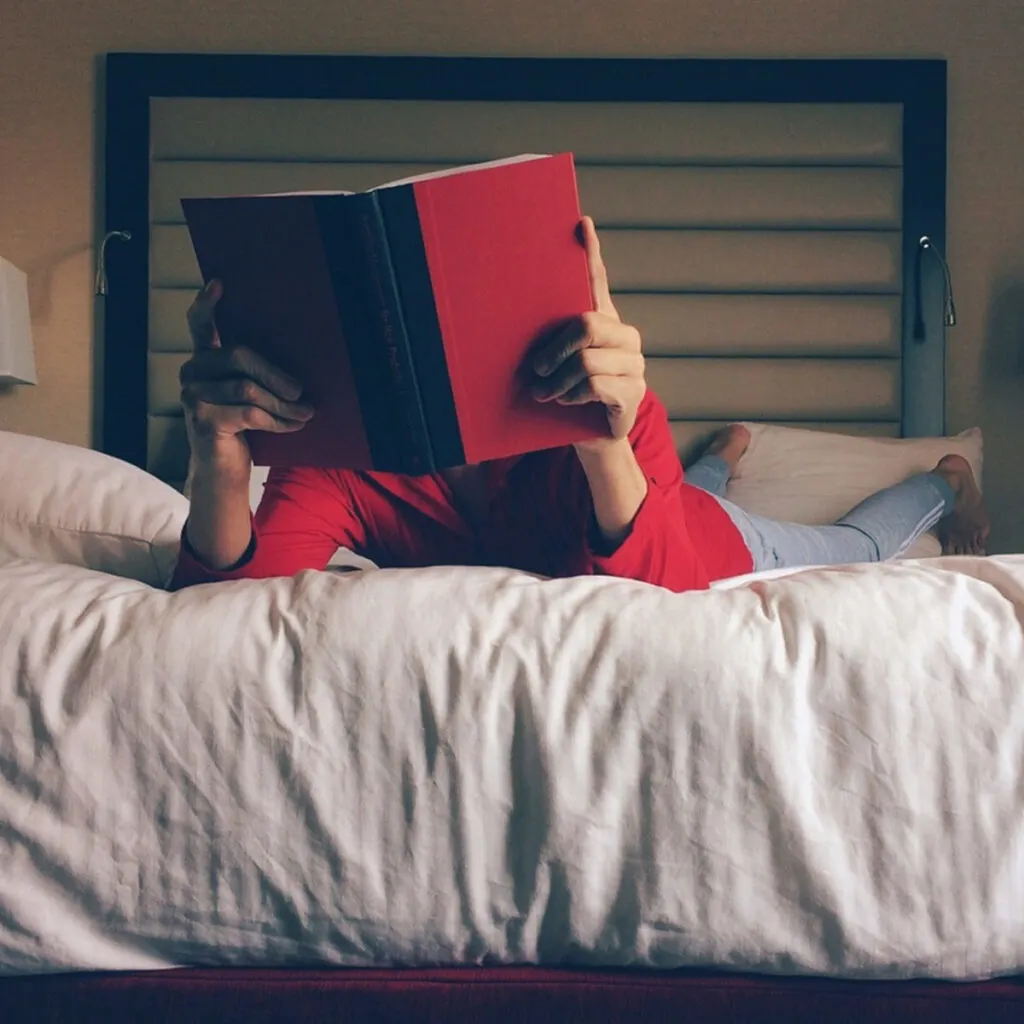 Person laying on a bed reading a book