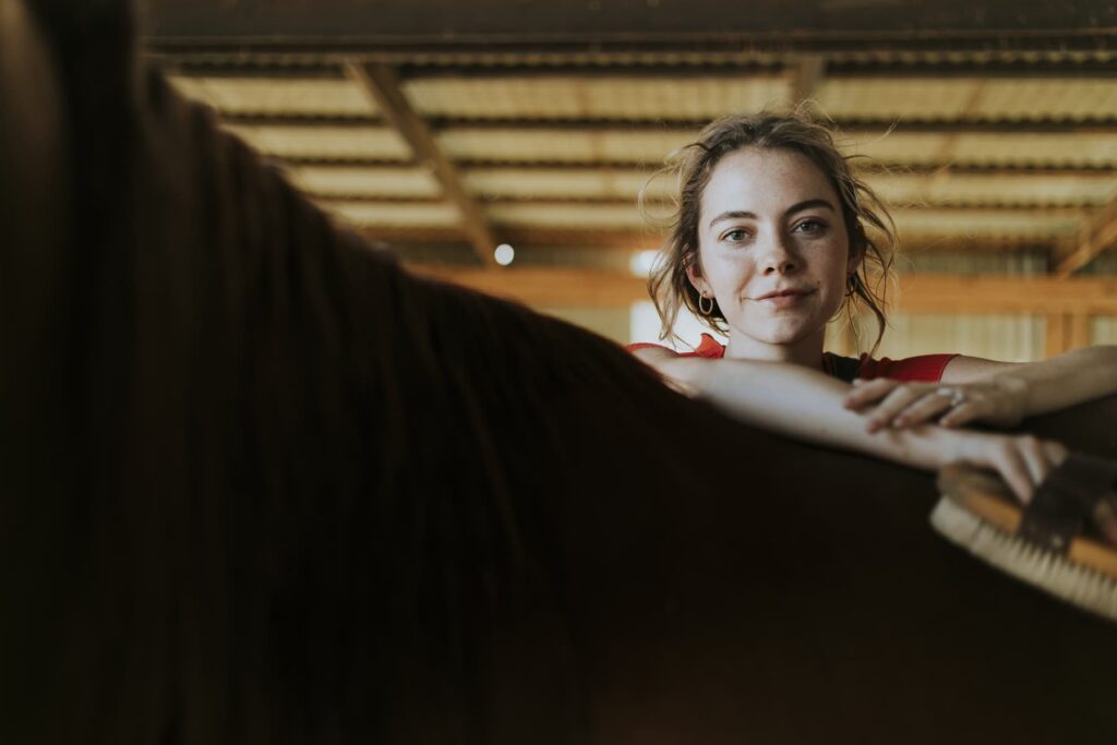 A girl learns over a horse's back.