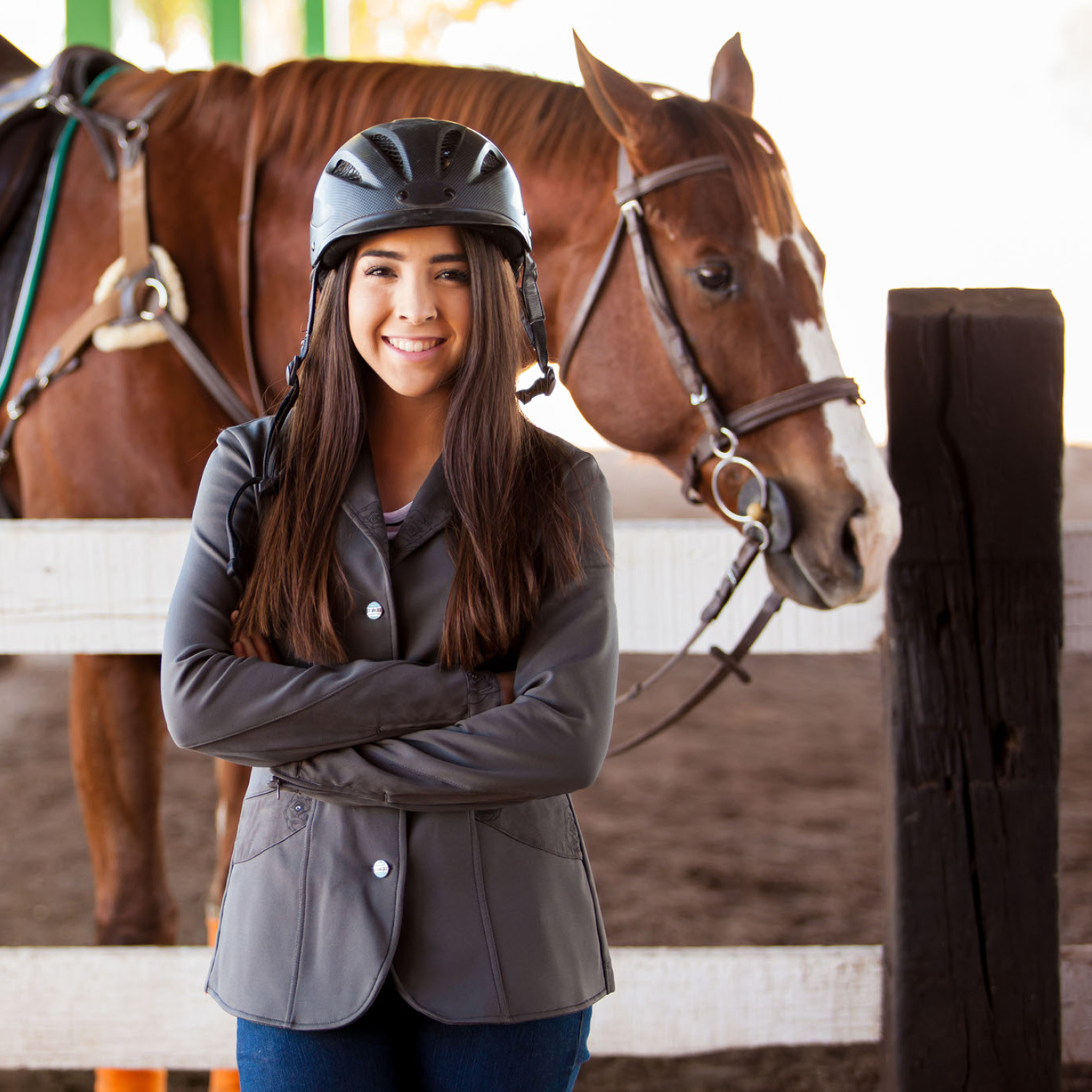 A young woman smiles in front of a beginner horse.