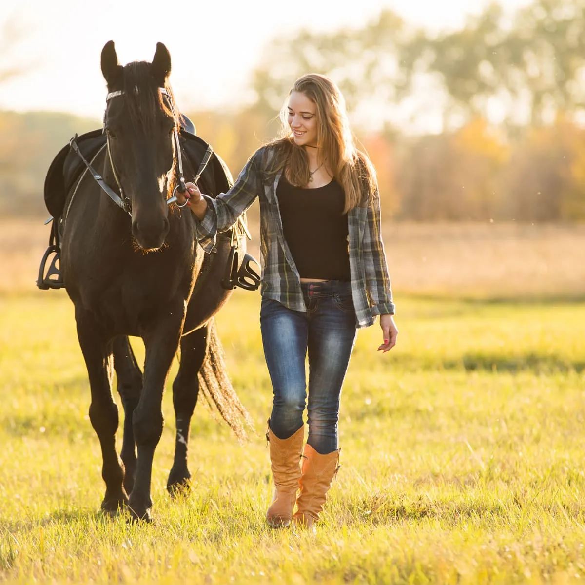 A girl walks a horse during golden hour.