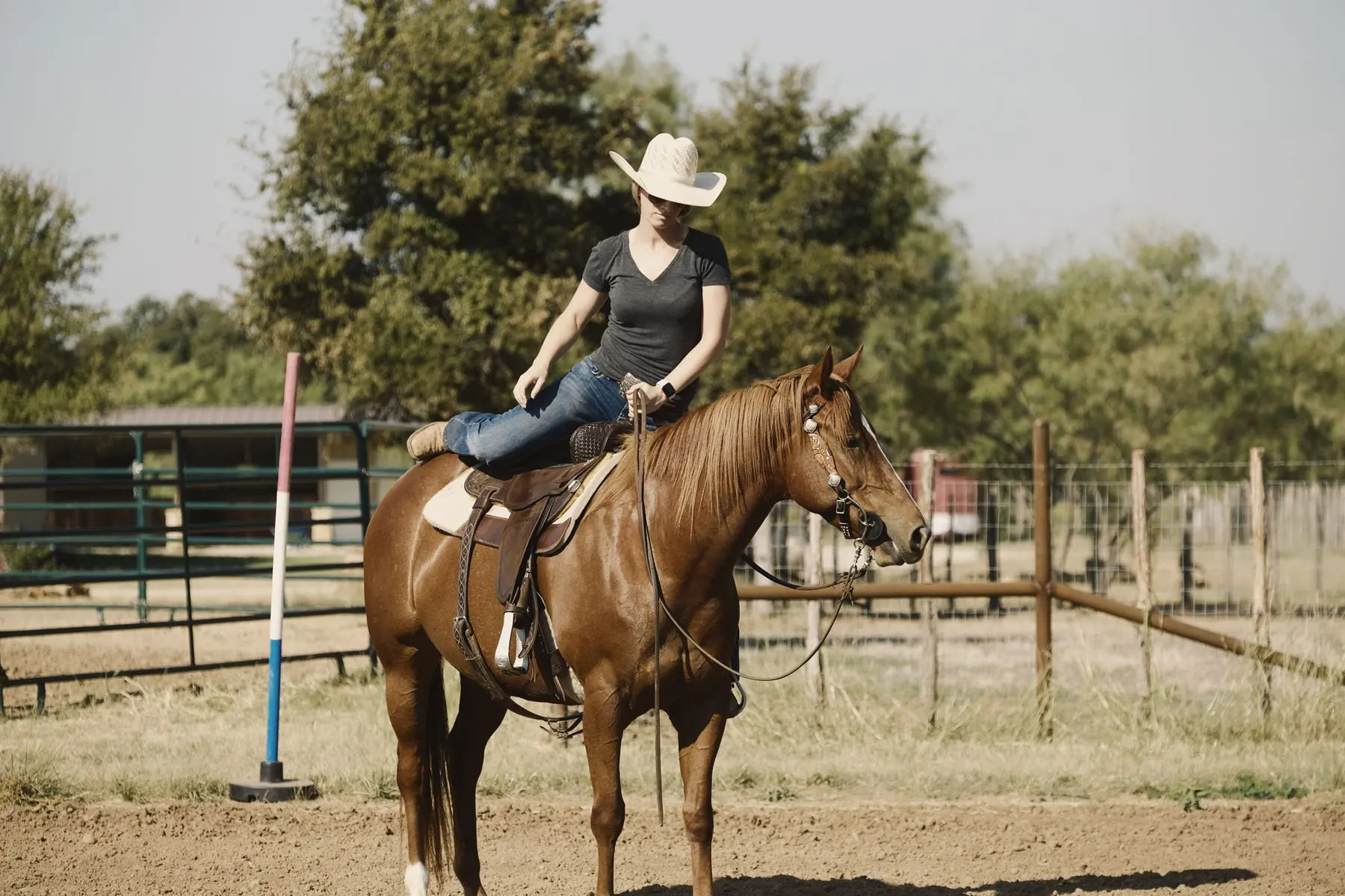 woman swinging her leg over a western saddle as she mounts a horse standing still for mounting.